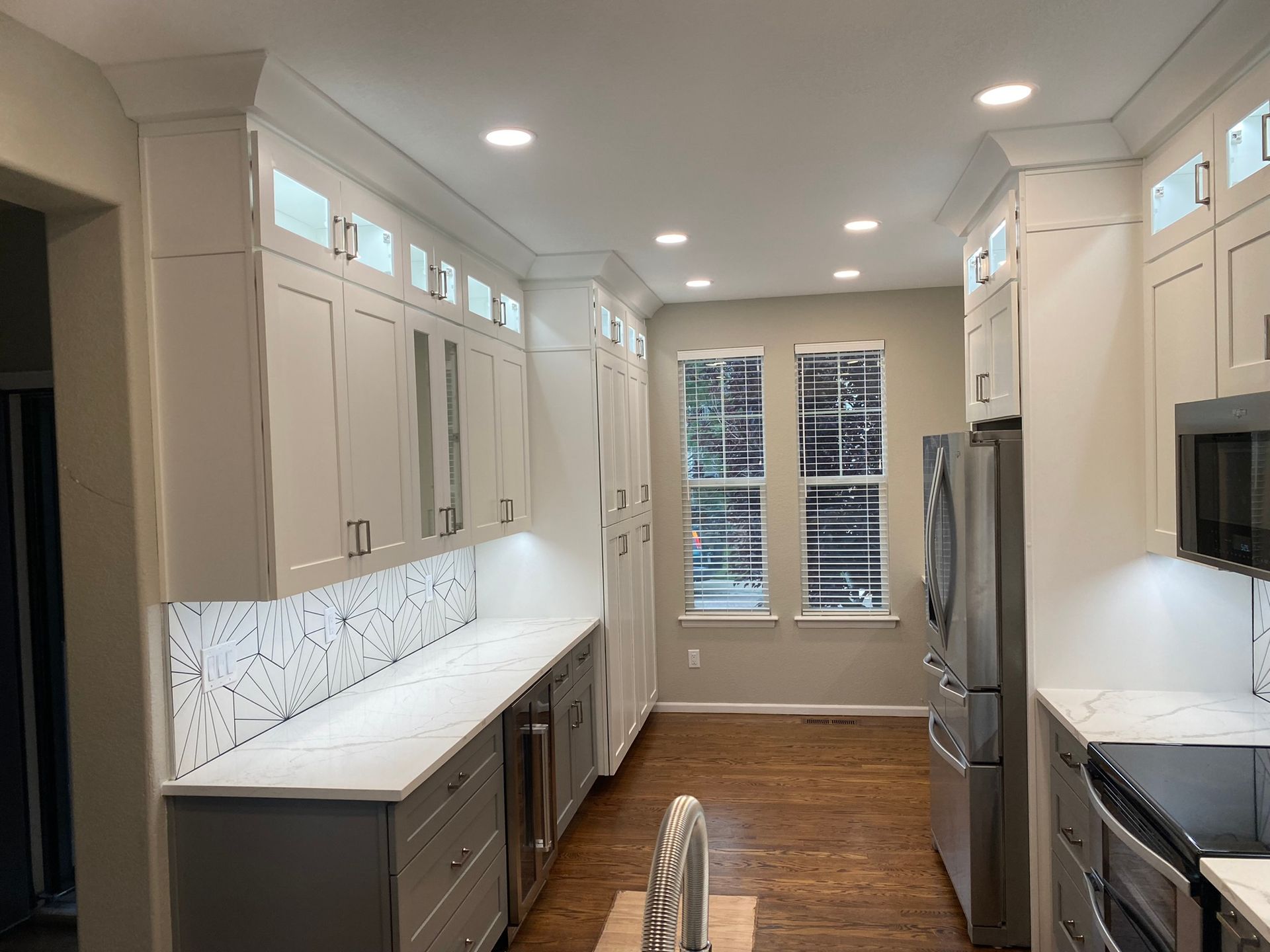 White kitchen with cabinets, countertops, stainless steel appliances, and a window.