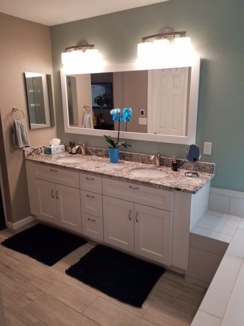 Bathroom with white vanity, double sinks, and a large mirror. Blue-green and beige walls.