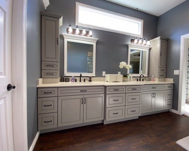 Gray bathroom vanity with matching cabinets, white countertop, dark floor.