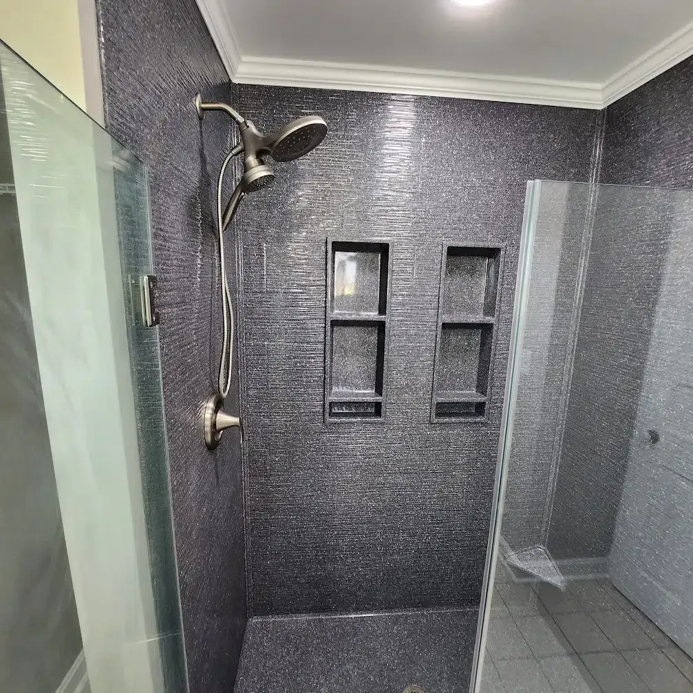 Bathroom shower with dark mosaic tile walls and glass doors.