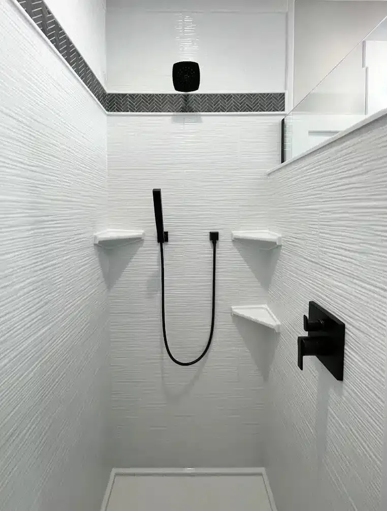White textured shower with black fixtures and shelves; showerhead, handheld shower, and control.
