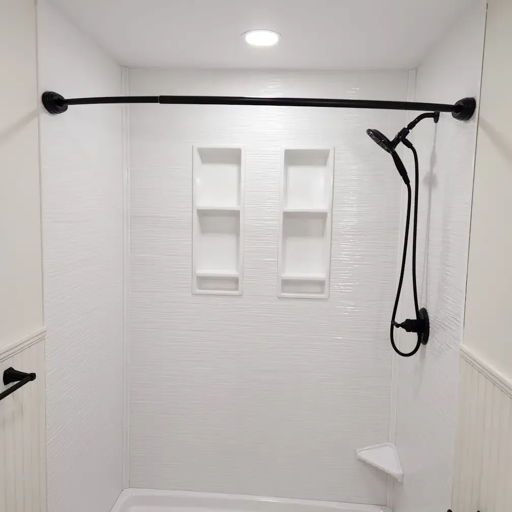 White shower with black fixtures and built-in shelves.