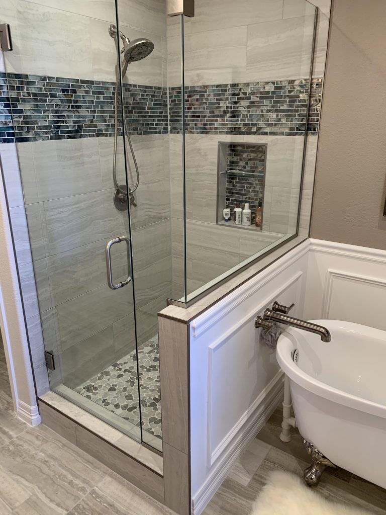 Modern bathroom with glass shower, mosaic tile accent, and clawfoot bathtub.