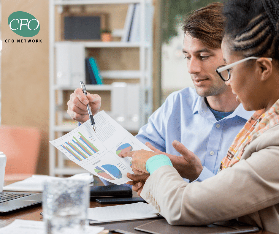 A man and a woman are sitting at a table looking at a financial report.