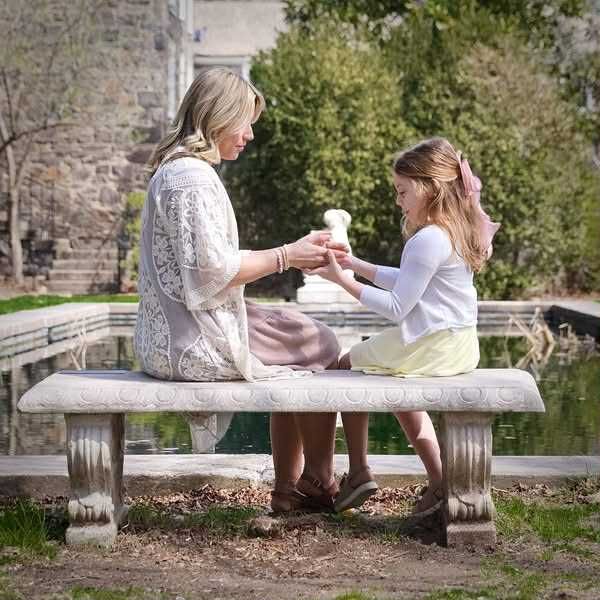 mother and daughter sitting on stone bench