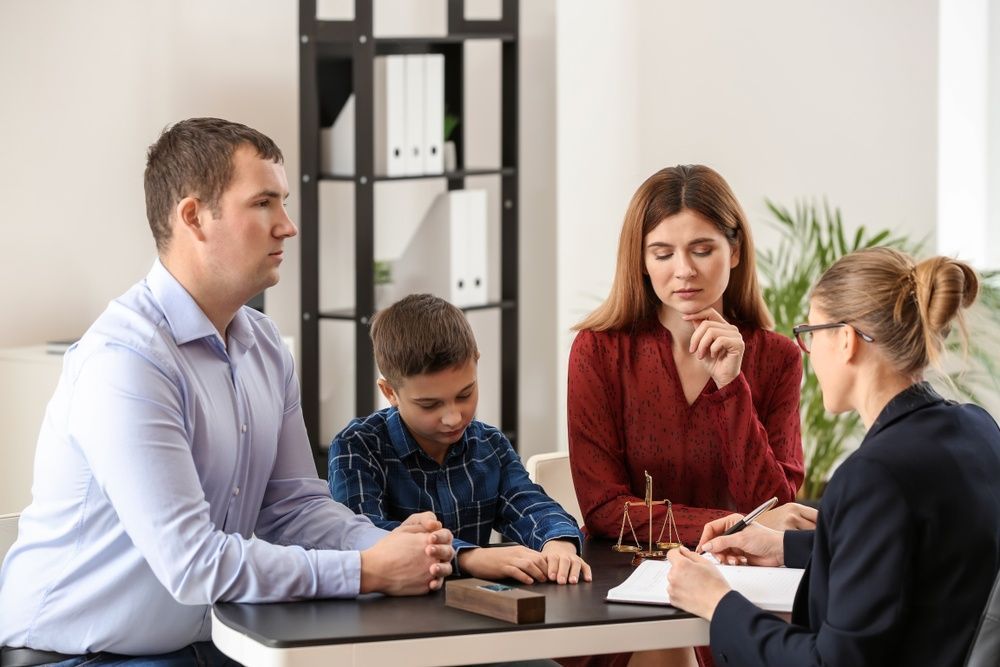 A Family is Sitting at a Table Talking to a Lawyer — McVittie Legal In Ballina, NSW