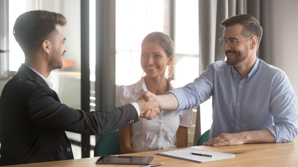 A Man and a Woman Are Shaking Hands While Sitting at a Table — McVittie Legal In Ballina, NSW