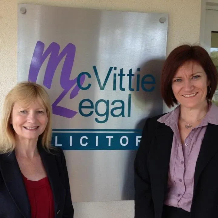 Close up of owners standing in front of McVittie Legal sign — McVittie Legal In Ballina, NSW