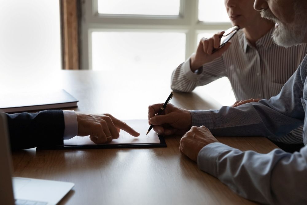 Two Men Are Sitting at a Table Looking at a Tablet — McVittie Legal In Ballina, NSW