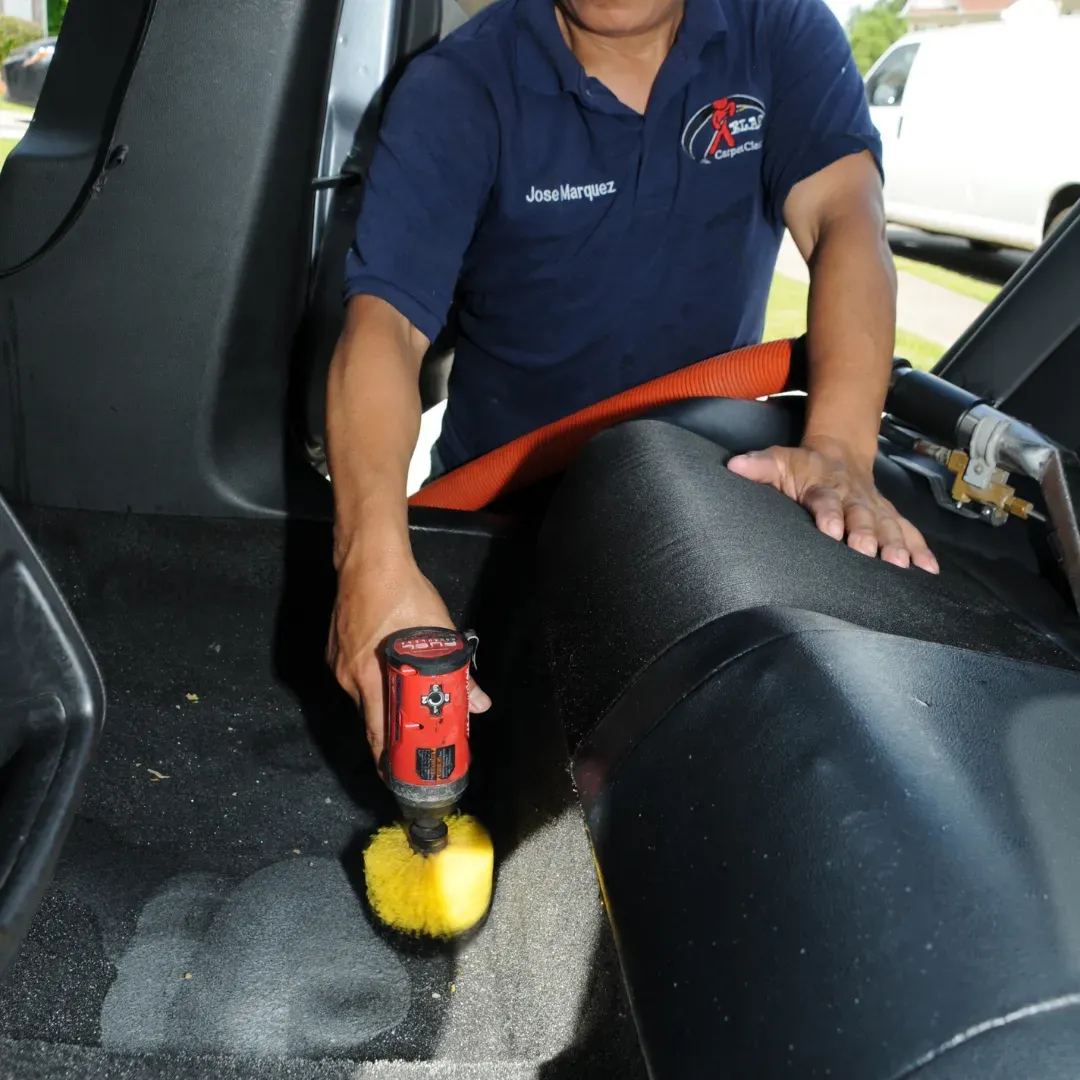 Blas Carpet technician agitating stains on auto carpet using the upholstery shampooing method.