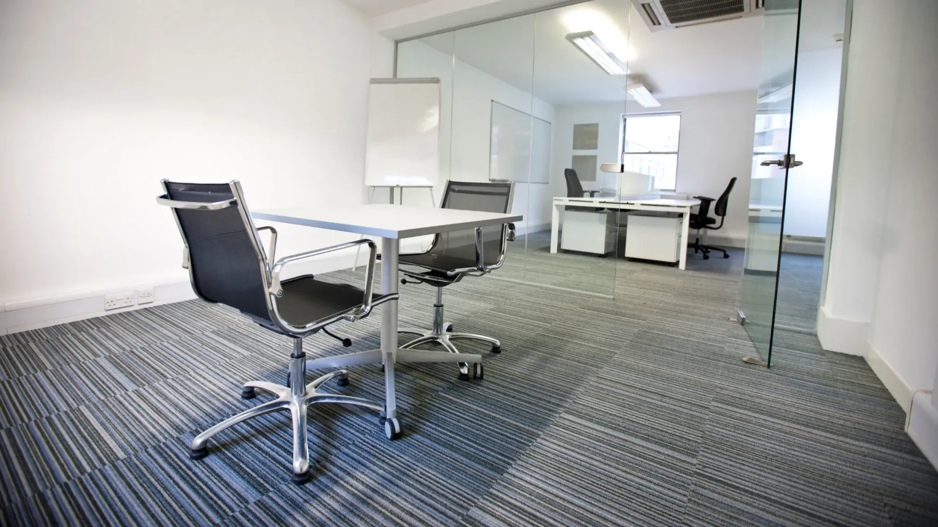 Carpeted office space with table and two chairs.