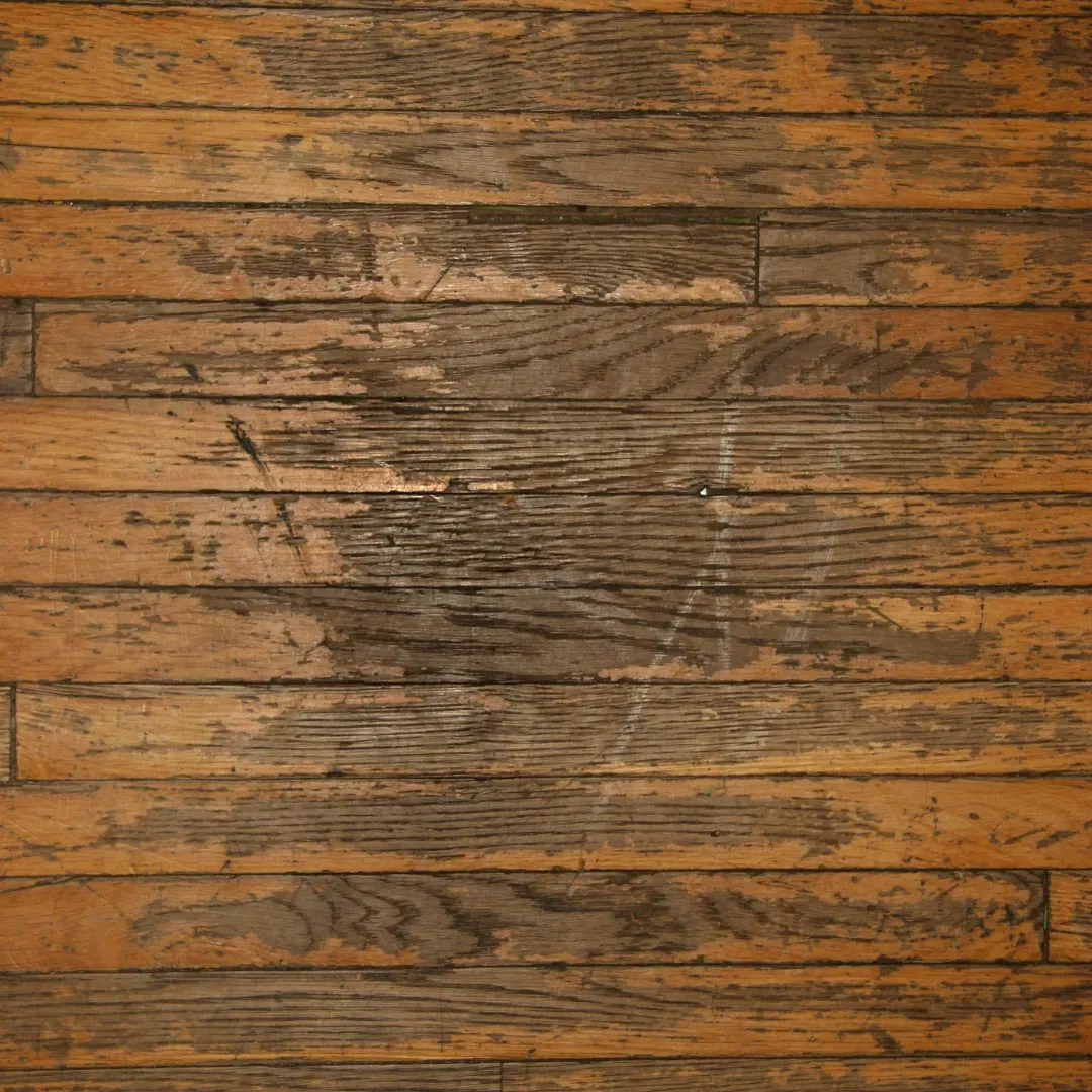 Hardwood floor with scratches and surface damage before refinishing service.