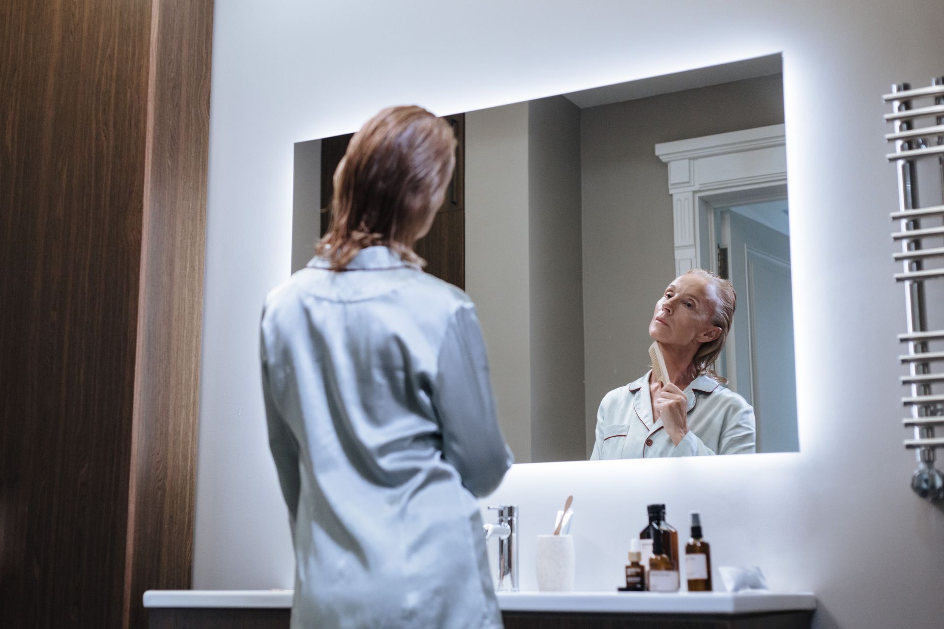 Mature woman examining her skin in a mirror as part of her skincare routine