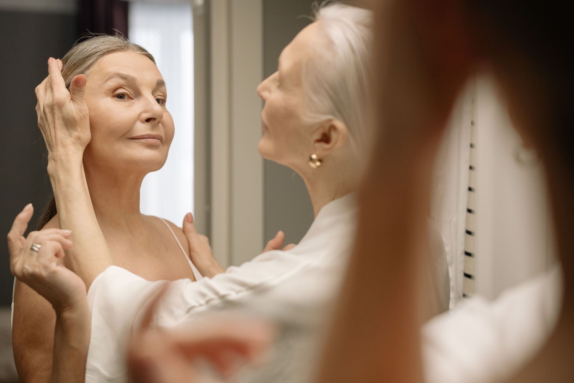 Mature woman examining her skin in a mirror as part of her skincare routine
