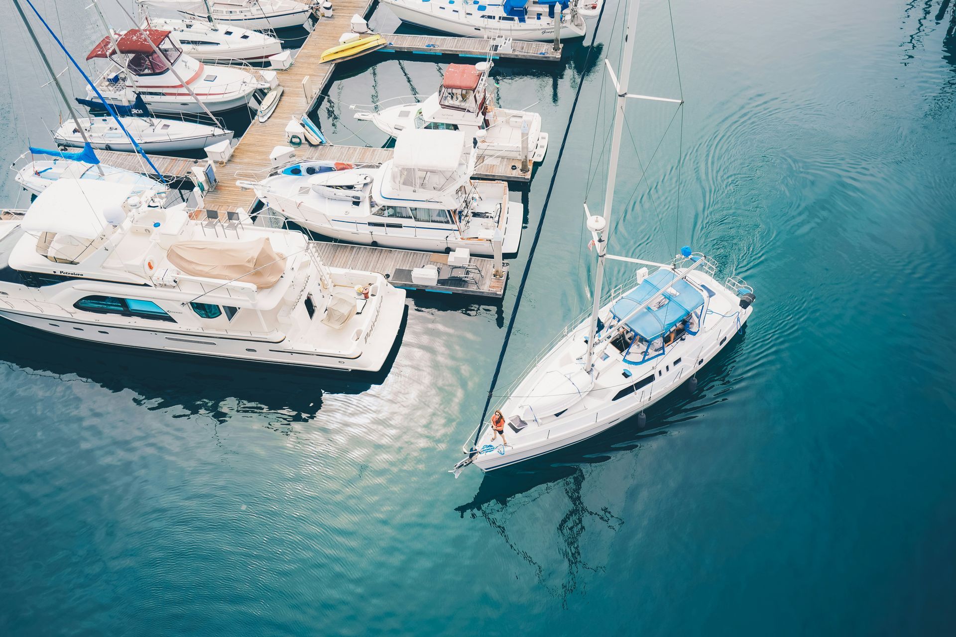 An aerial view of a marina with boats docked and a sailboat in the water.