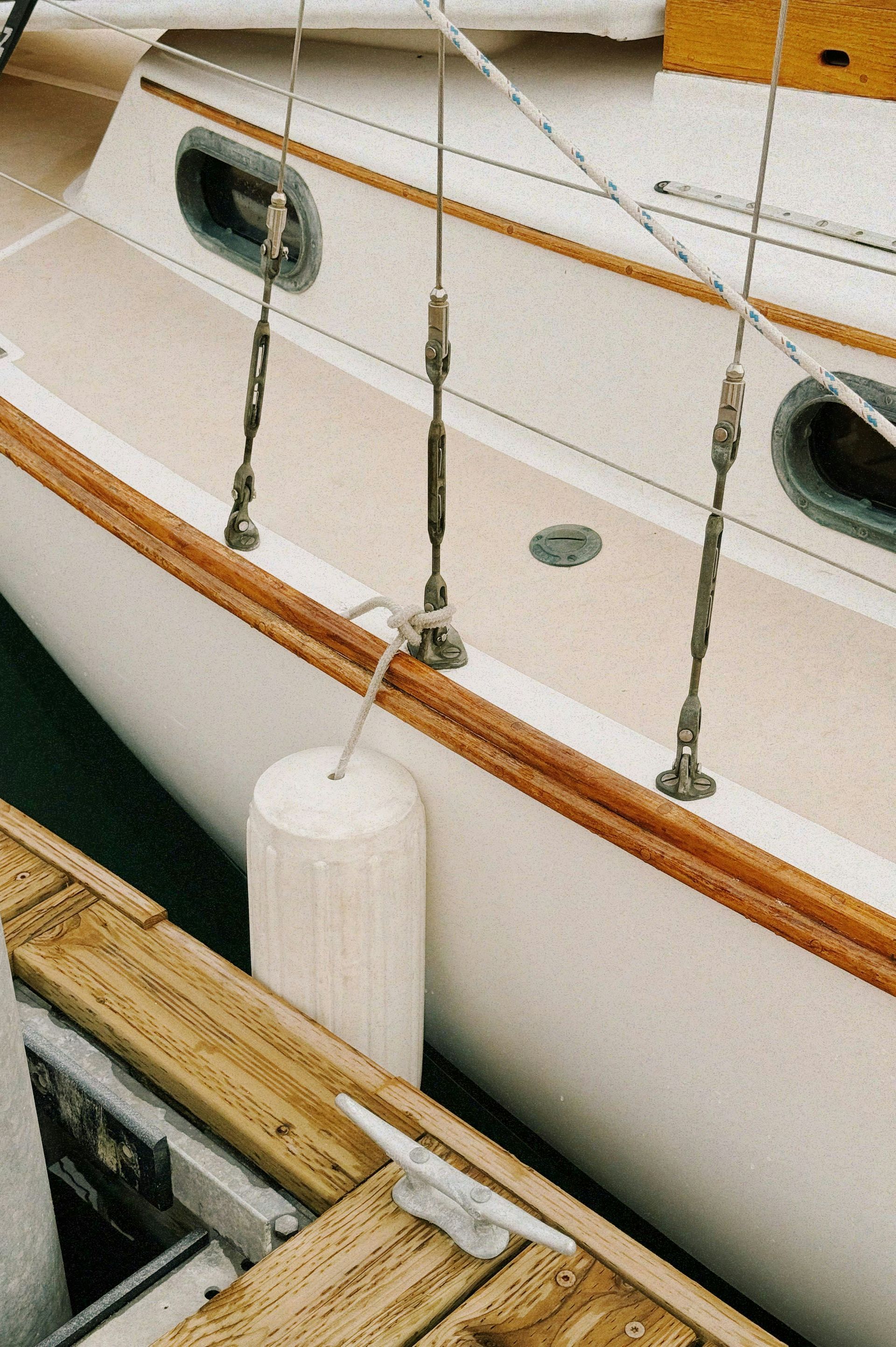 A boat is docked at a dock with a white fender