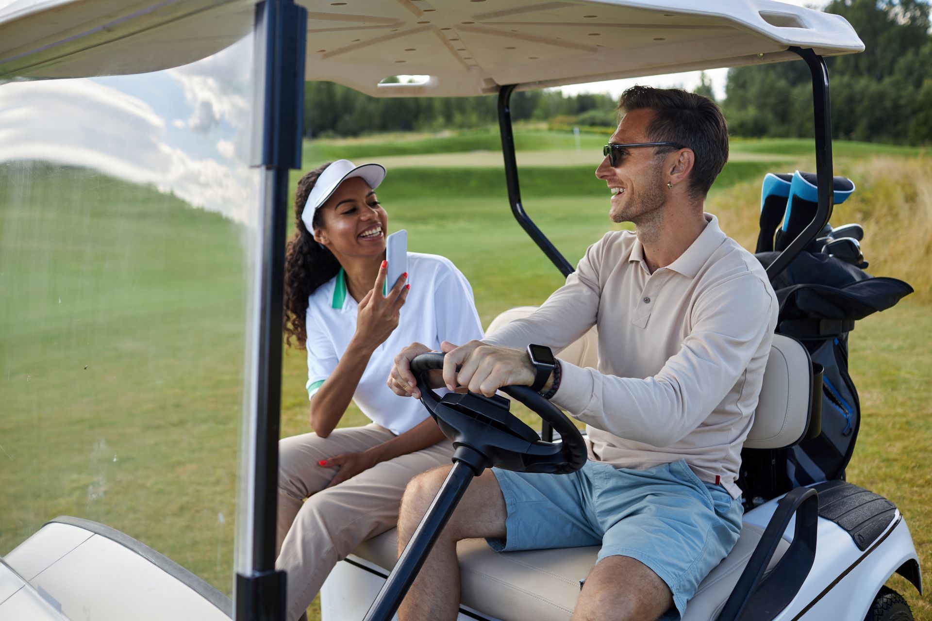 A man and a woman are sitting in a golf cart on a golf course.
