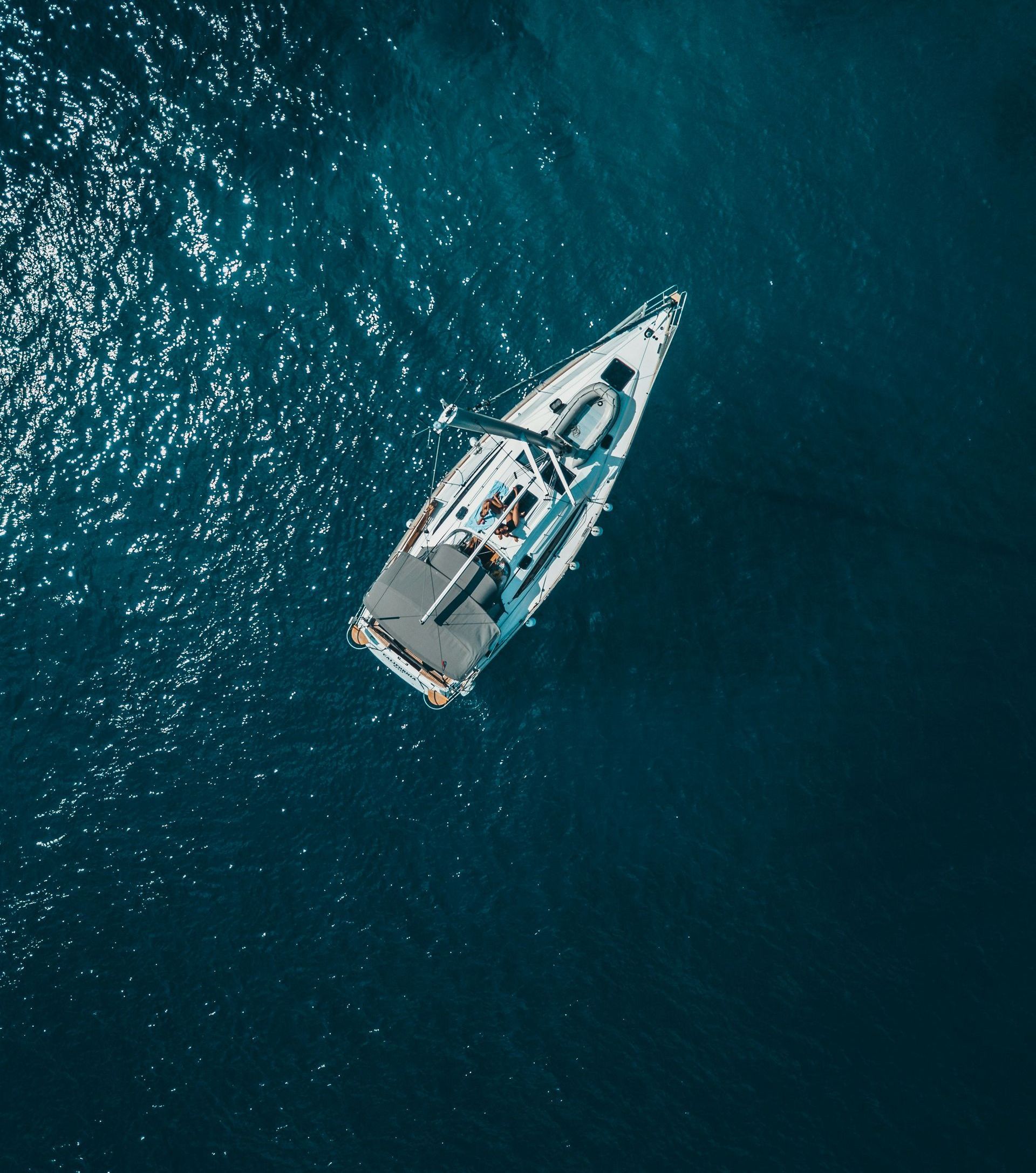 An aerial view of a sailboat in the ocean.