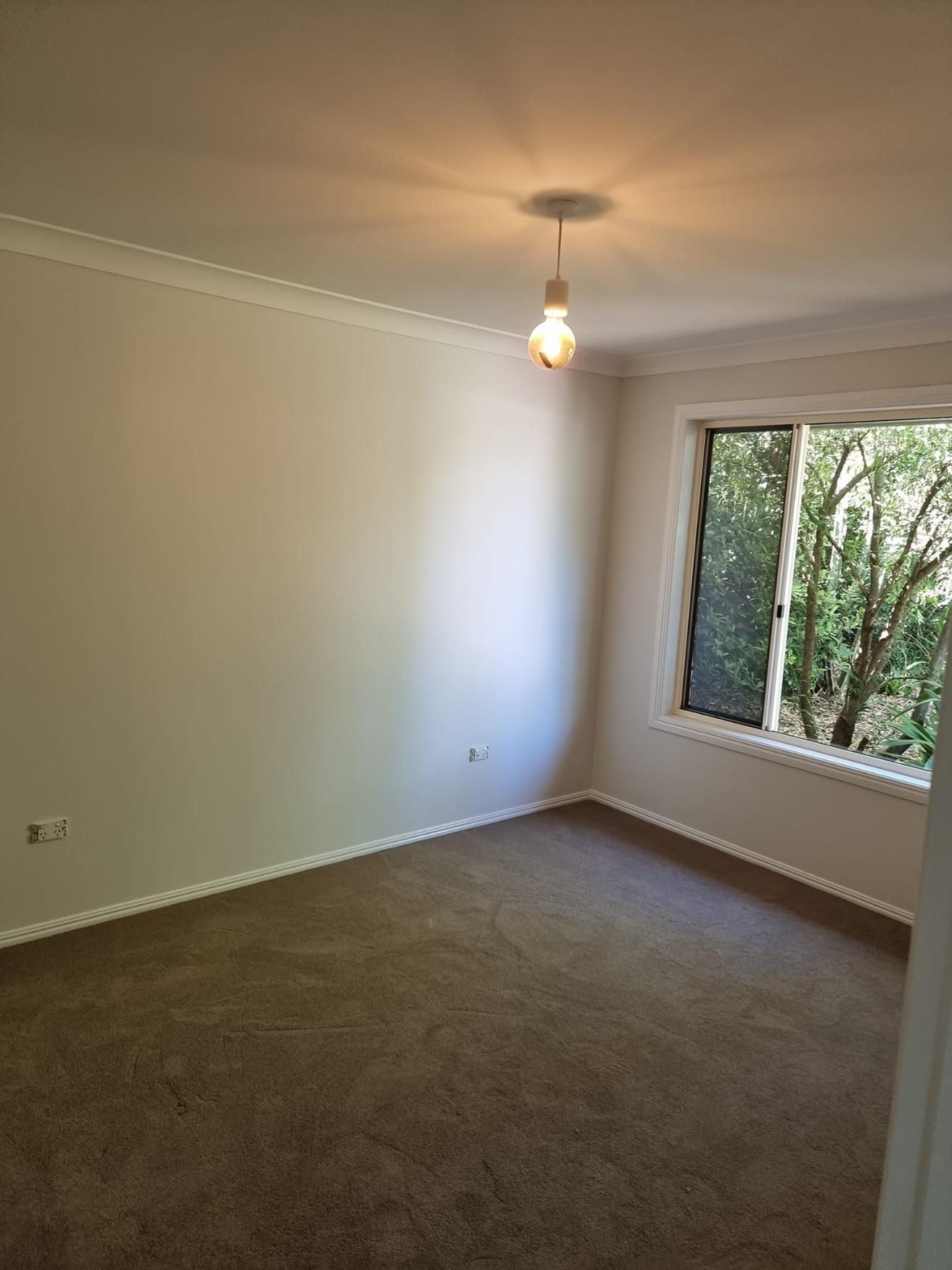 An Empty Room With A Window And A Light Hanging From The Ceiling — LMS Painting & Maintenance Pty Ltd In Singleton, NSW