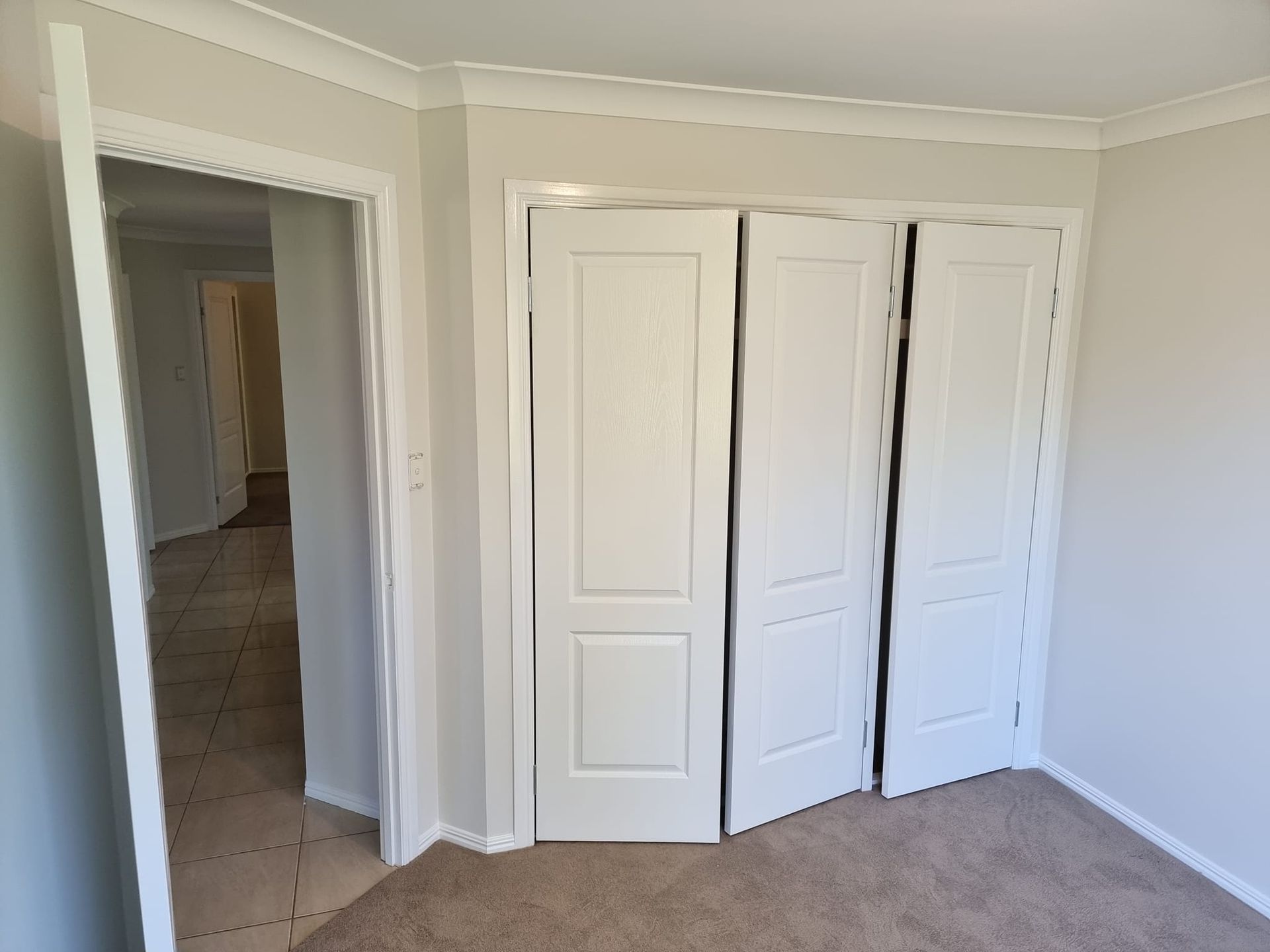 An Empty Room With White Doors And A Carpeted Floor — LMS Painting & Maintenance Pty Ltd In Charlestown, NSW