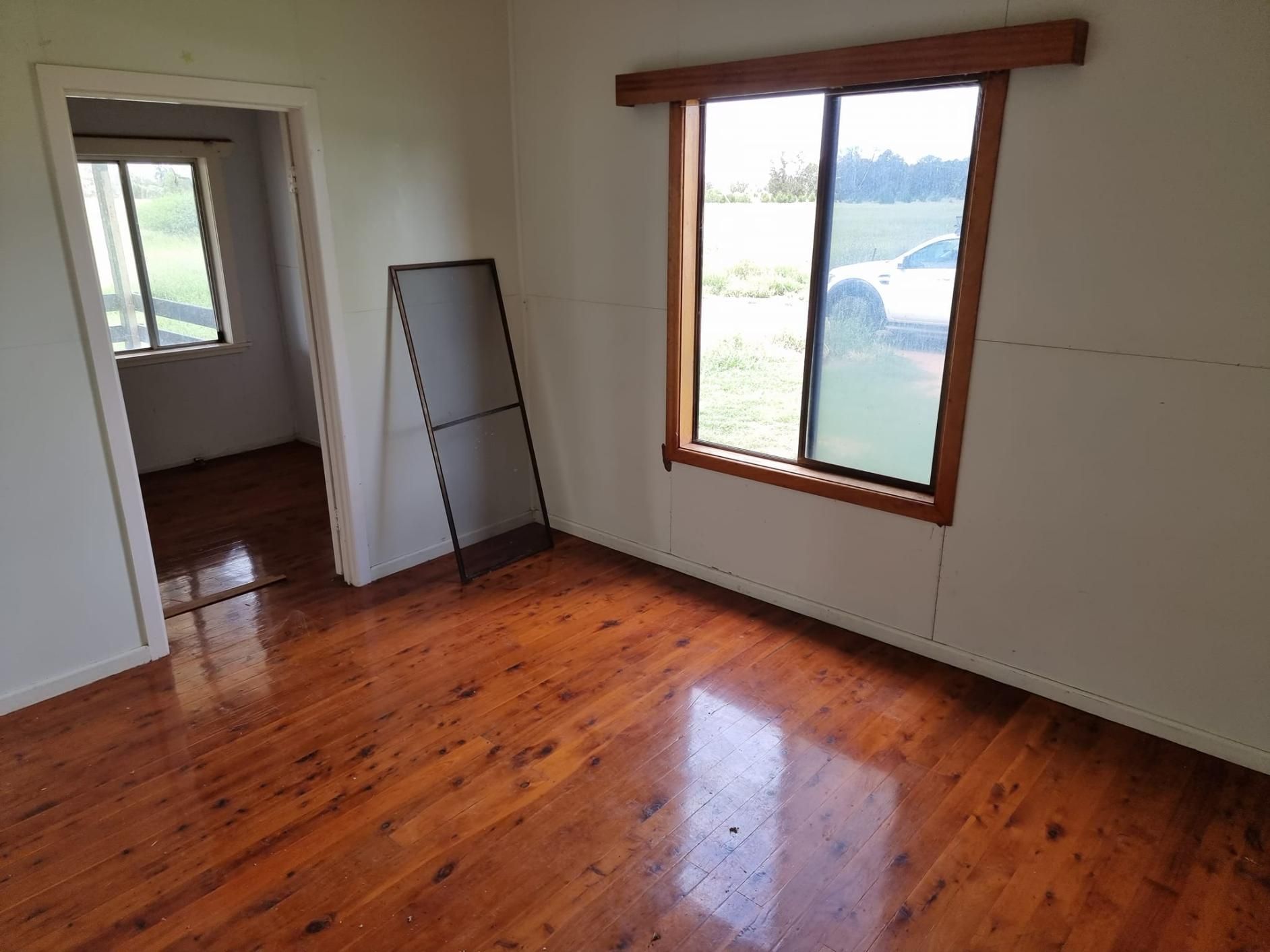 An Empty Room With A Wooden Floor And A Window — LMS Painting & Maintenance Pty Ltd In North Lambton, NSW