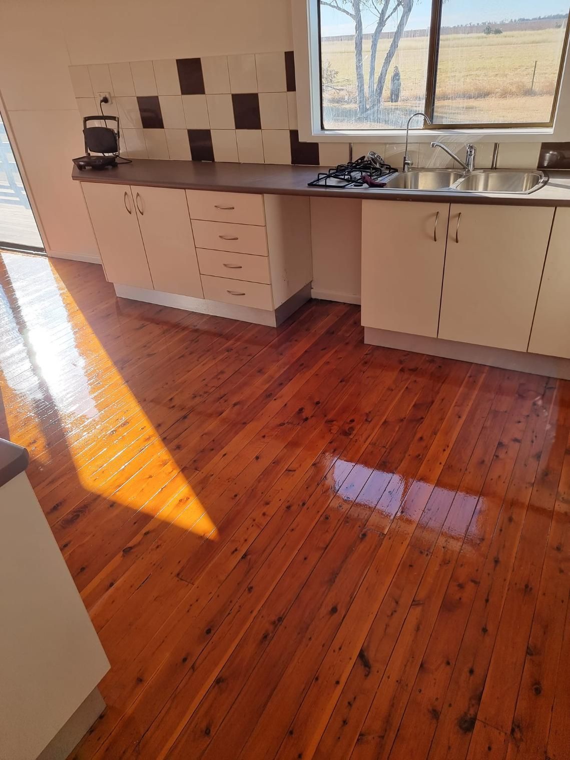A Kitchen With Wooden Floors And White Cabinets And A Sink — LMS Painting & Maintenance Pty Ltd In Maitland, NSW