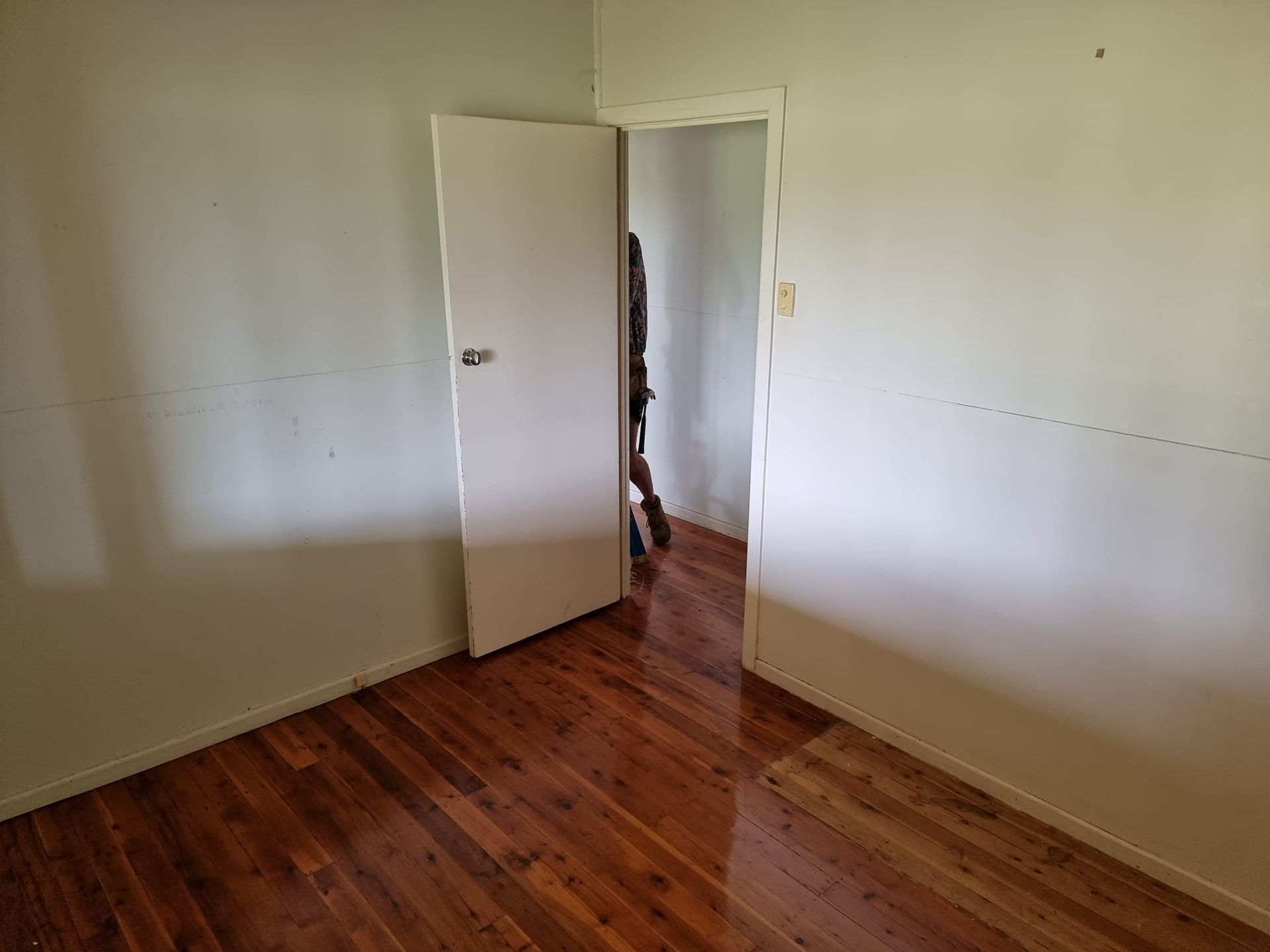 An Empty Room With Hardwood Floors And A White Door — LMS Painting & Maintenance Pty Ltd In North Lambton, NSW
