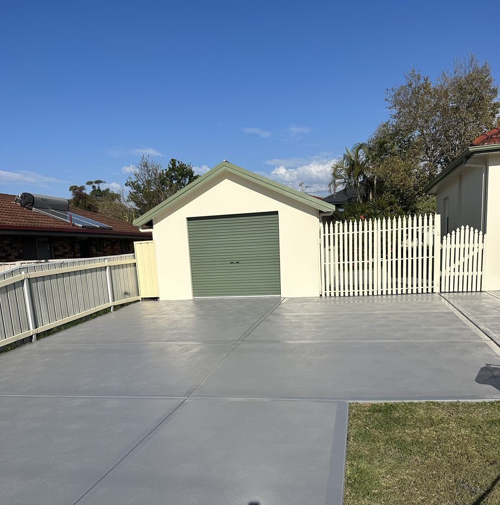A concrete driveway leading to a garage with a green door  — LMS Painting & Maintenance Pty Ltd In North Lambton, NSW