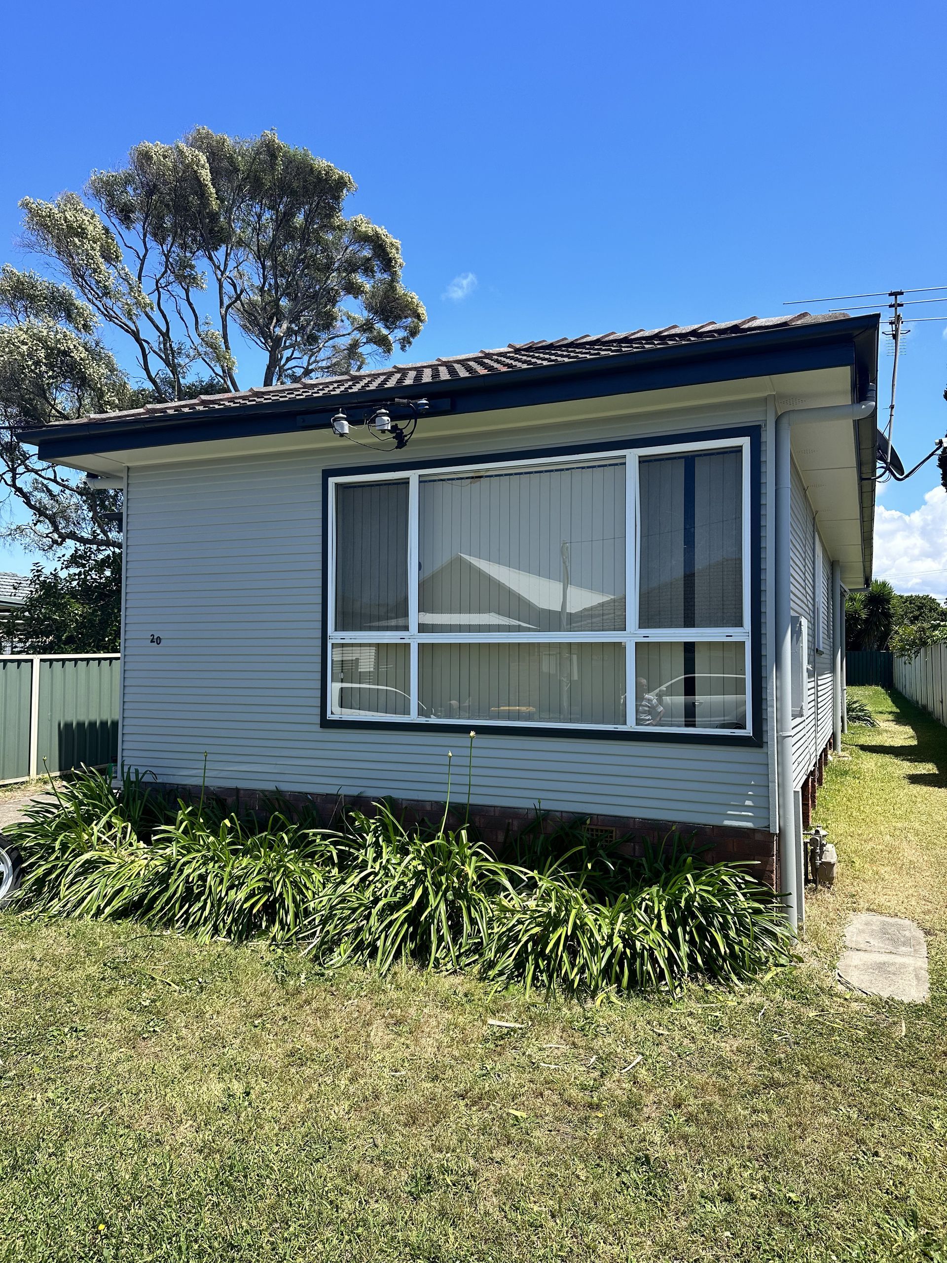 A small white house is sitting in the middle of a grassy field — LMS Painting & Maintenance Pty Ltd In North Lambton, NSW