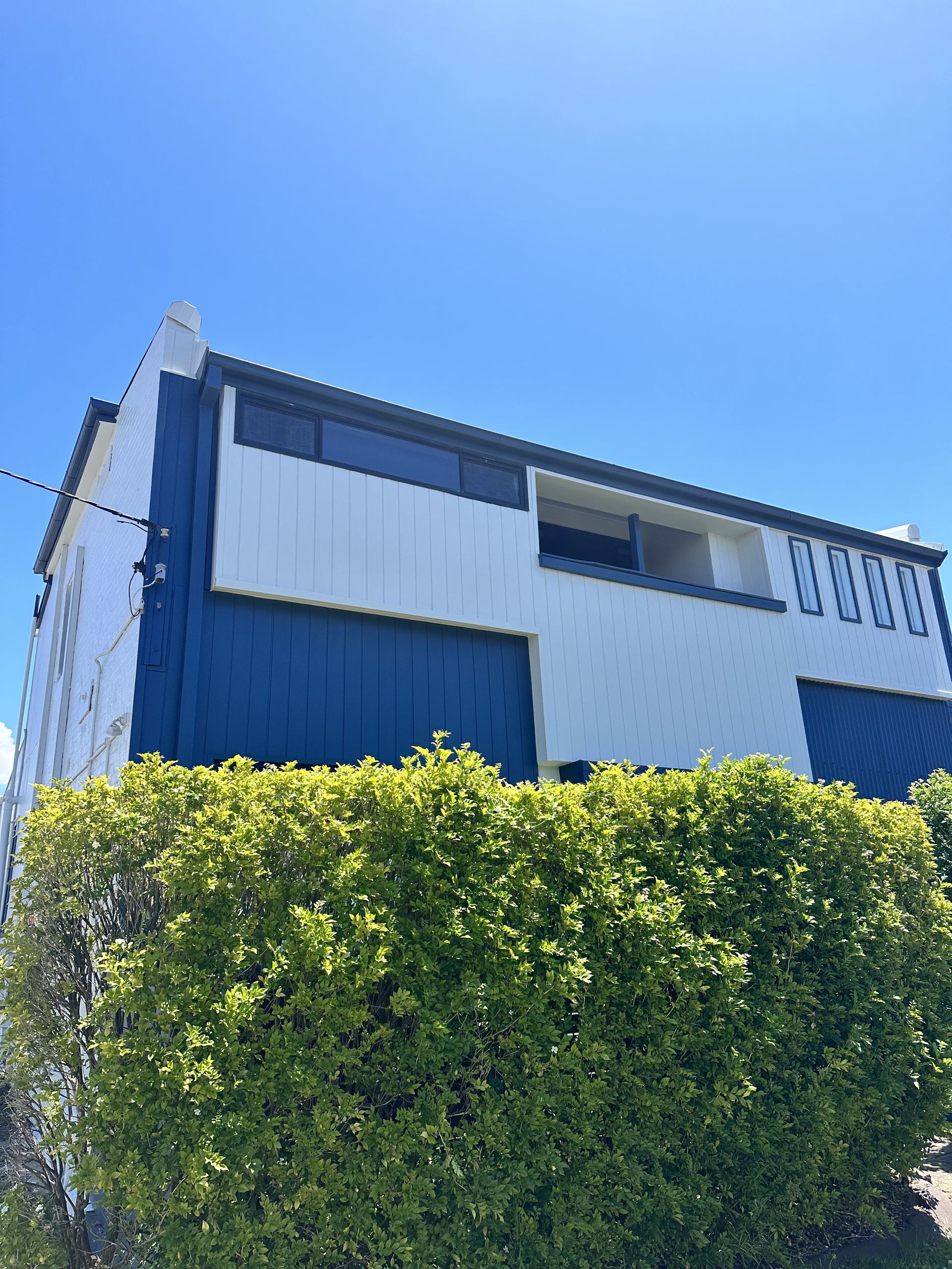 A blue and white house with a hedge in front of it — LMS Painting & Maintenance Pty Ltd In North Lambton, NSW
