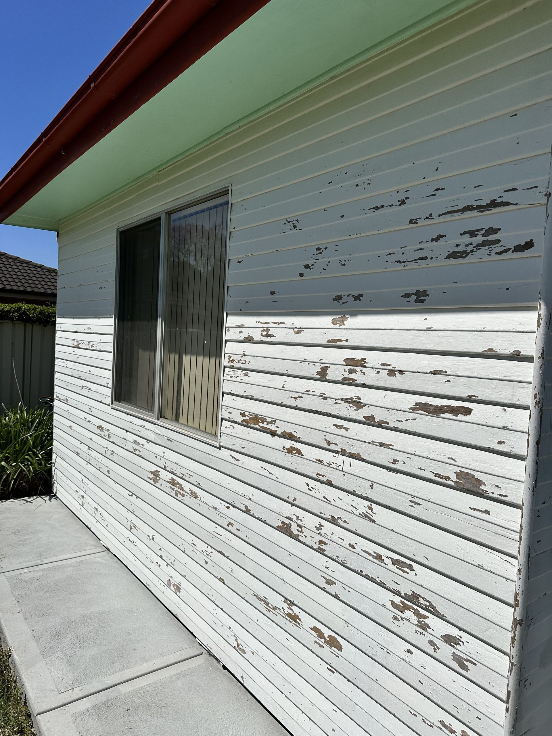 A white house with peeling paint and a window — LMS Painting & Maintenance Pty Ltd In North Lambton, NSW