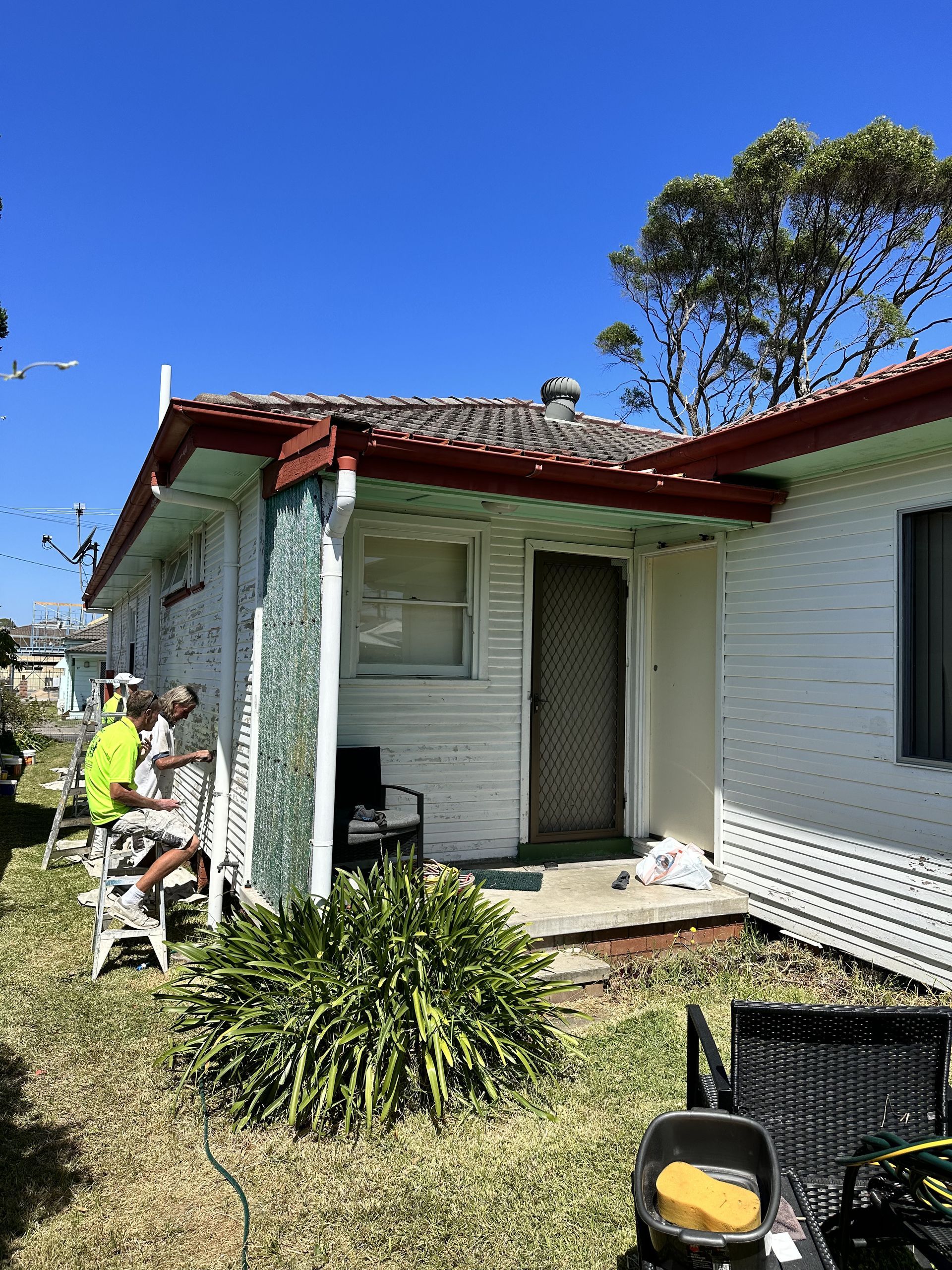 A group of people are sitting on a porch of a house — LMS Painting & Maintenance Pty Ltd In North Lambton, NSW