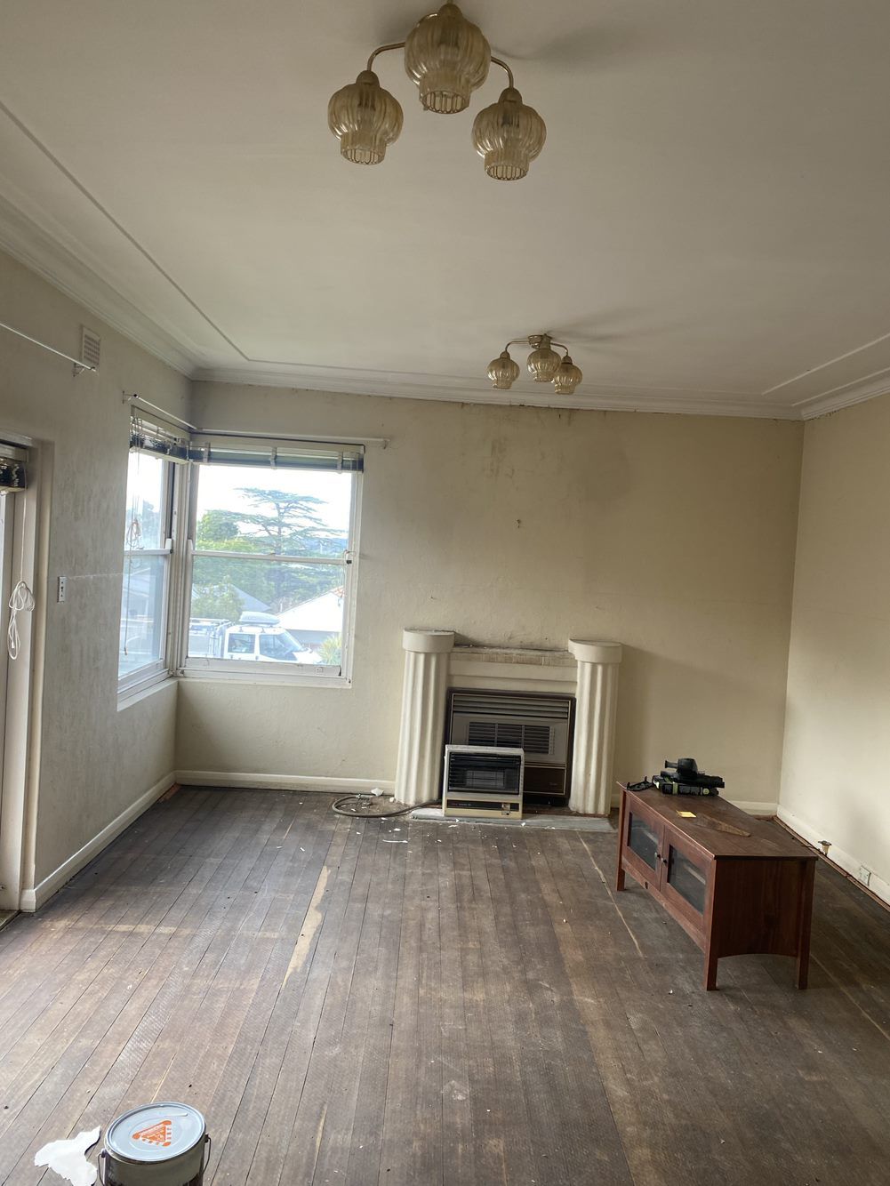 An empty living room with a fireplace and a chandelier — LMS Painting & Maintenance Pty Ltd In North Lambton, NSW