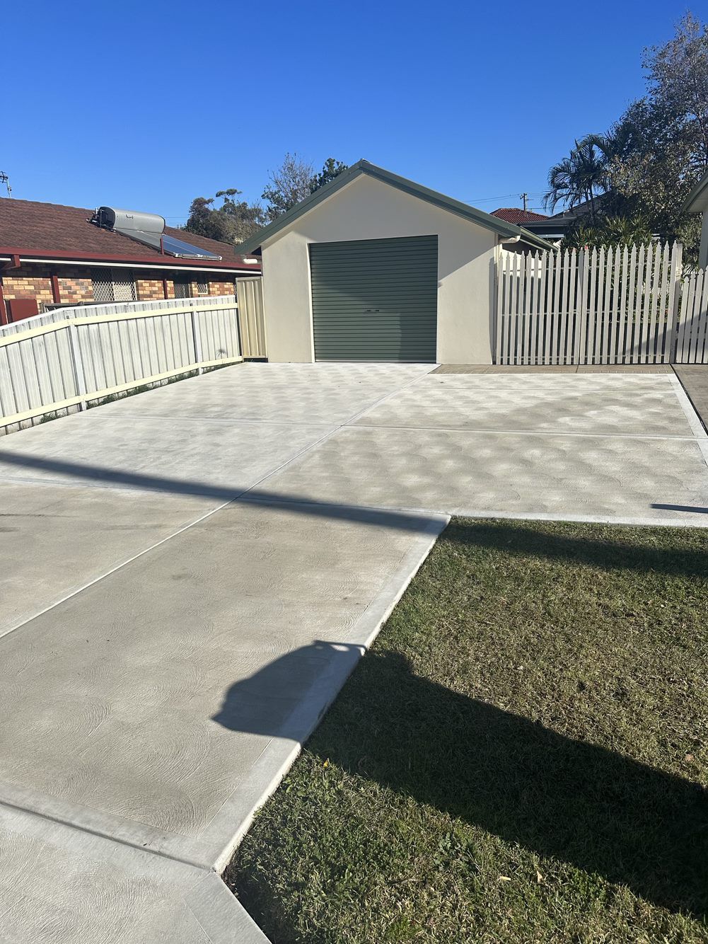 A concrete driveway leading to a garage with a green door  — LMS Painting & Maintenance Pty Ltd In North Lambton, NSW
