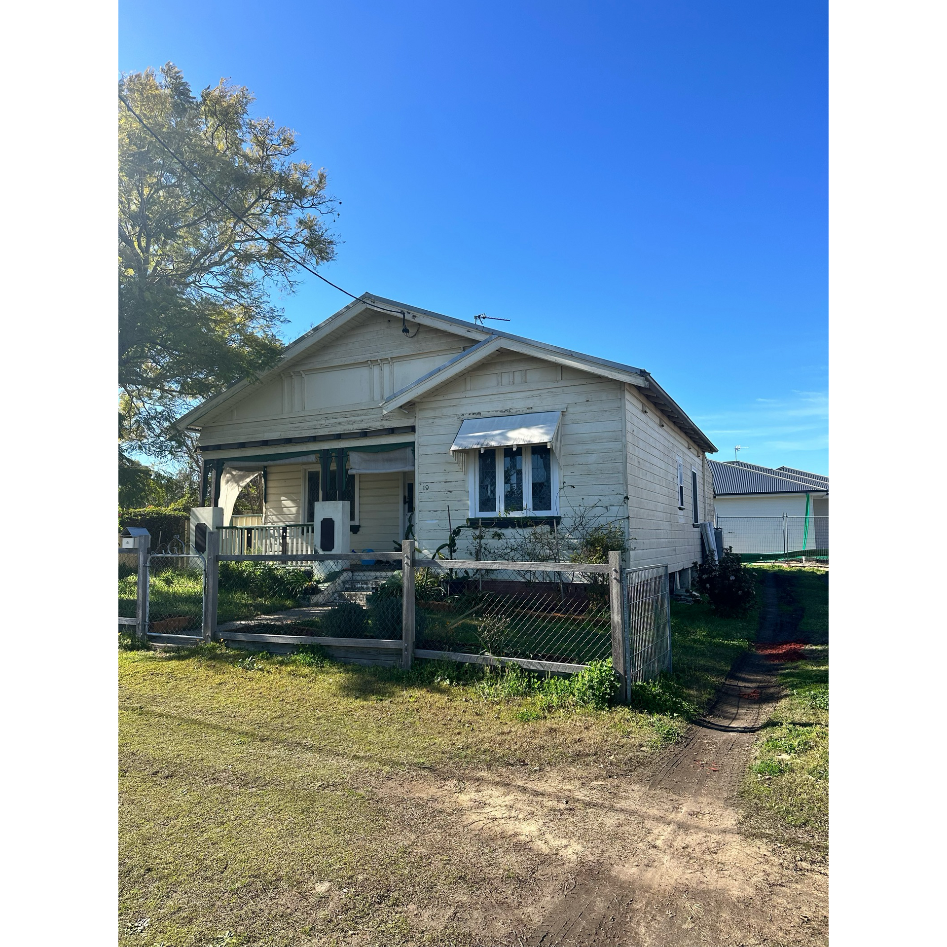 A small white house is sitting in the middle of a grassy field  — LMS Painting & Maintenance Pty Ltd In North Lambton, NSW