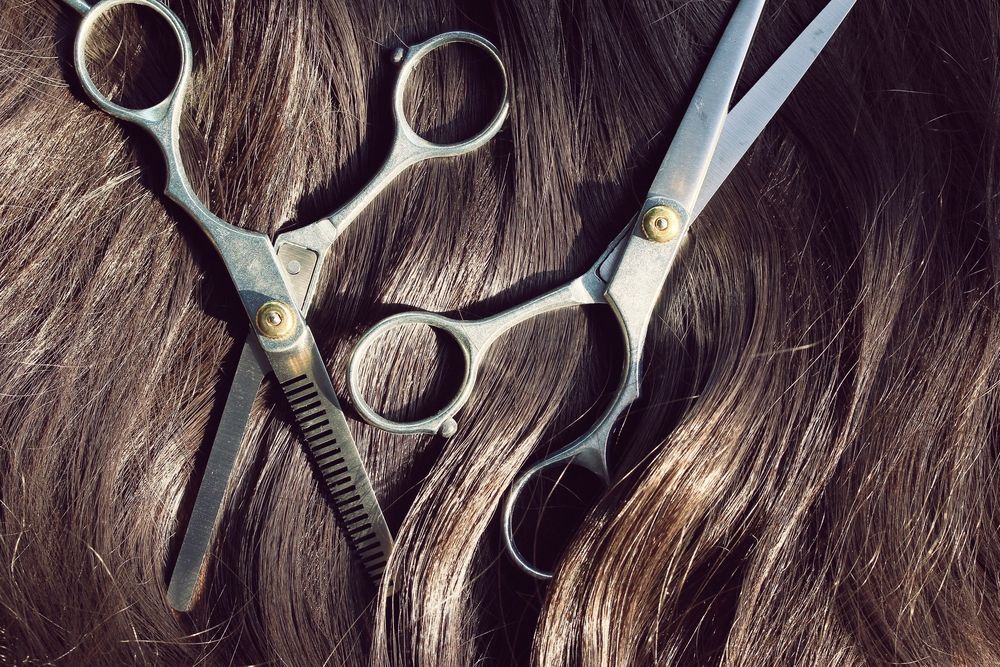 A pair of scissors laying on top of a woman 's hair.