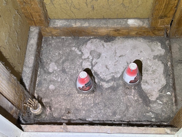 Two small canisters inside a stone alcove. Wooden framing surrounds the alcove. The canisters have red and white designs.