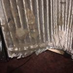 Damaged pleated blinds, with tears and debris, resting on carpet.