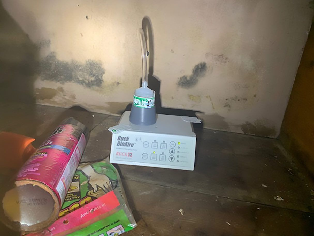 mold inspection houston tx A device with a silver tube and various buttons sits in a dimly lit space. Bottles and trash are on the floor.