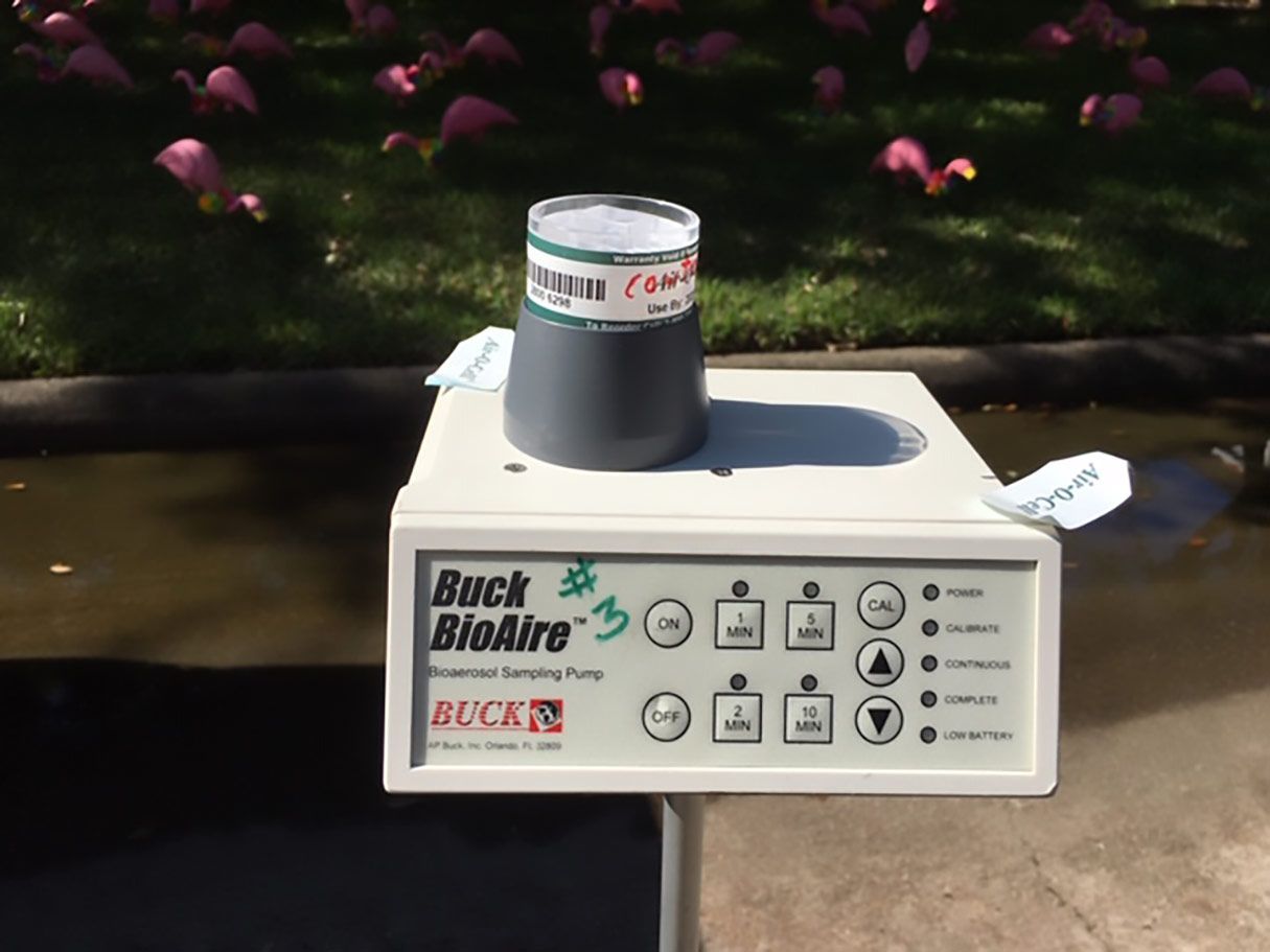 mold inspection houston tx A Buck BioAire air sampling pump with a cylindrical container on top, near a flamingo habitat.