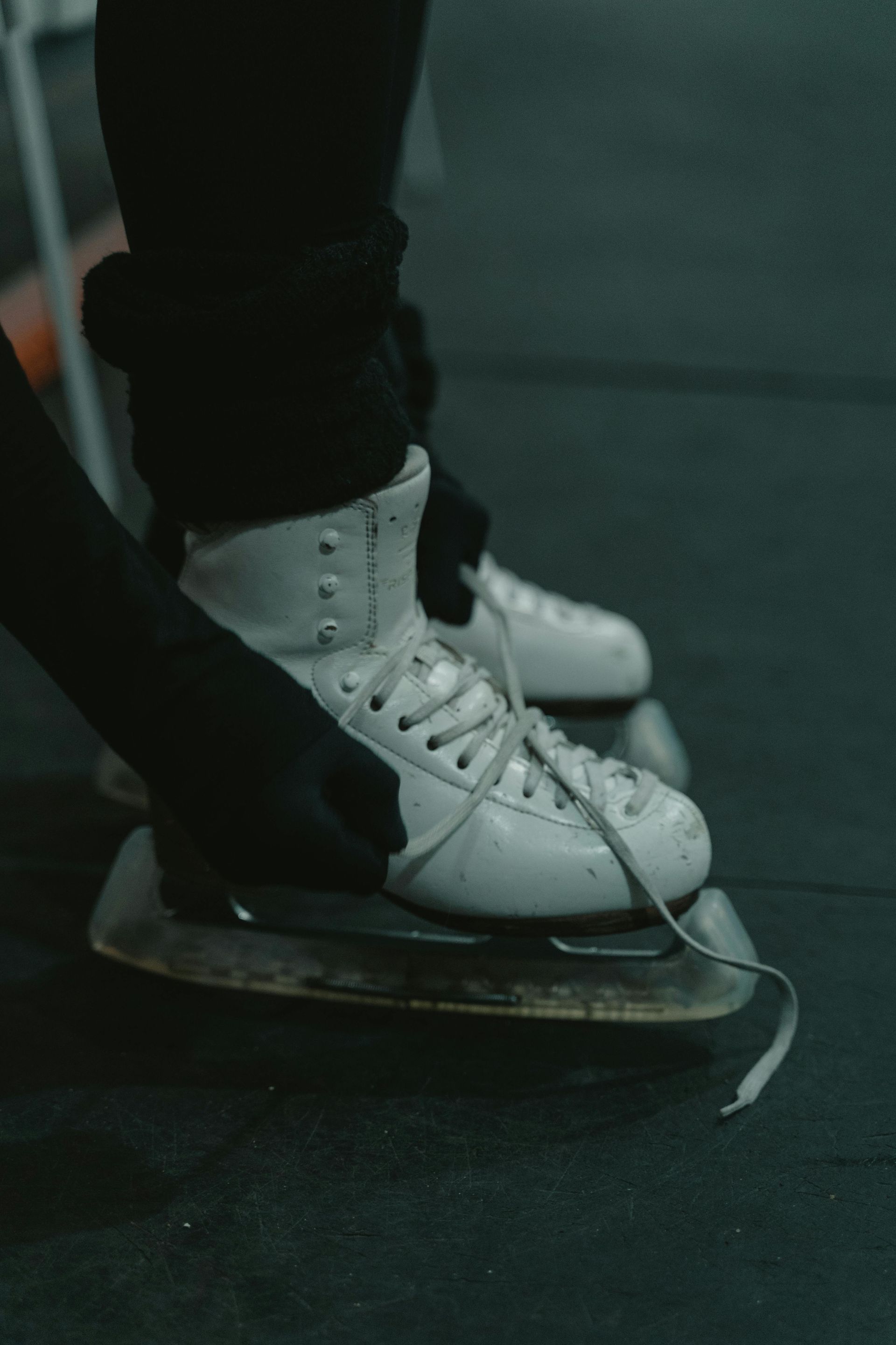 White ice skates on the ice, close-up of the skater’s feet.