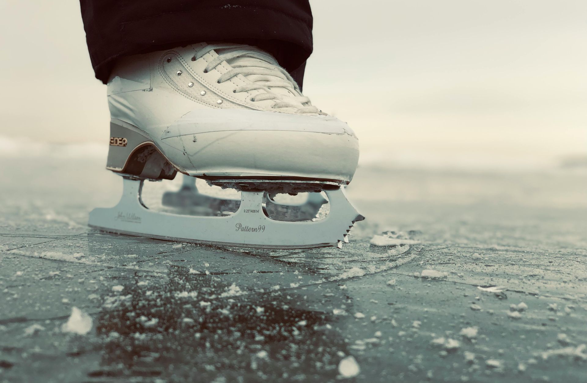 White ice skate gliding on a frozen surface with scattered ice chips