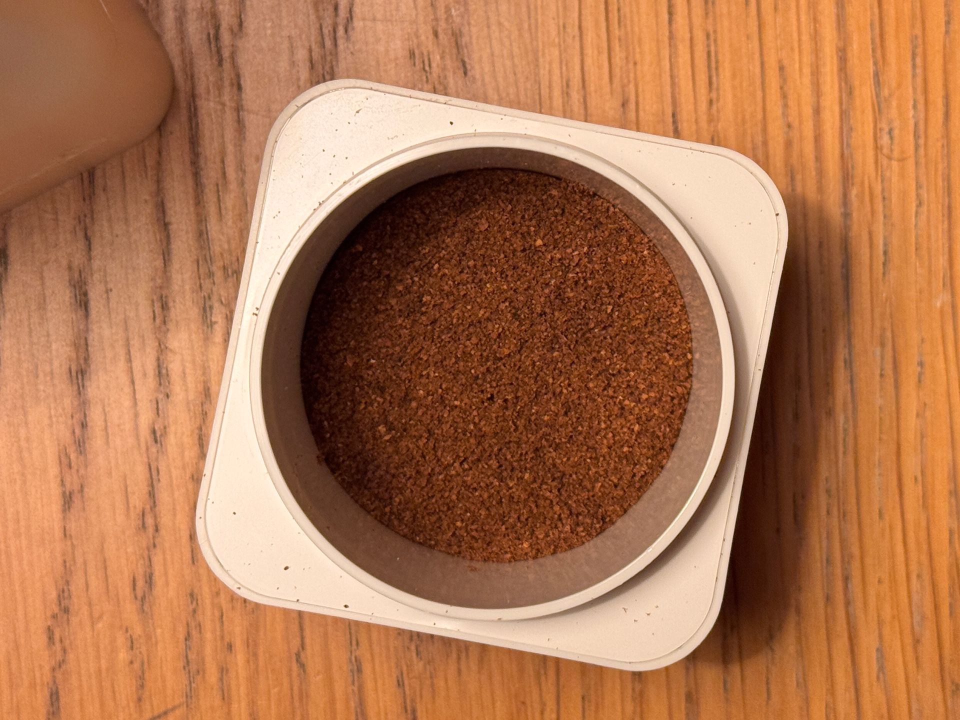 Black espresso maker and accessories in an open travel case on a wooden surface.