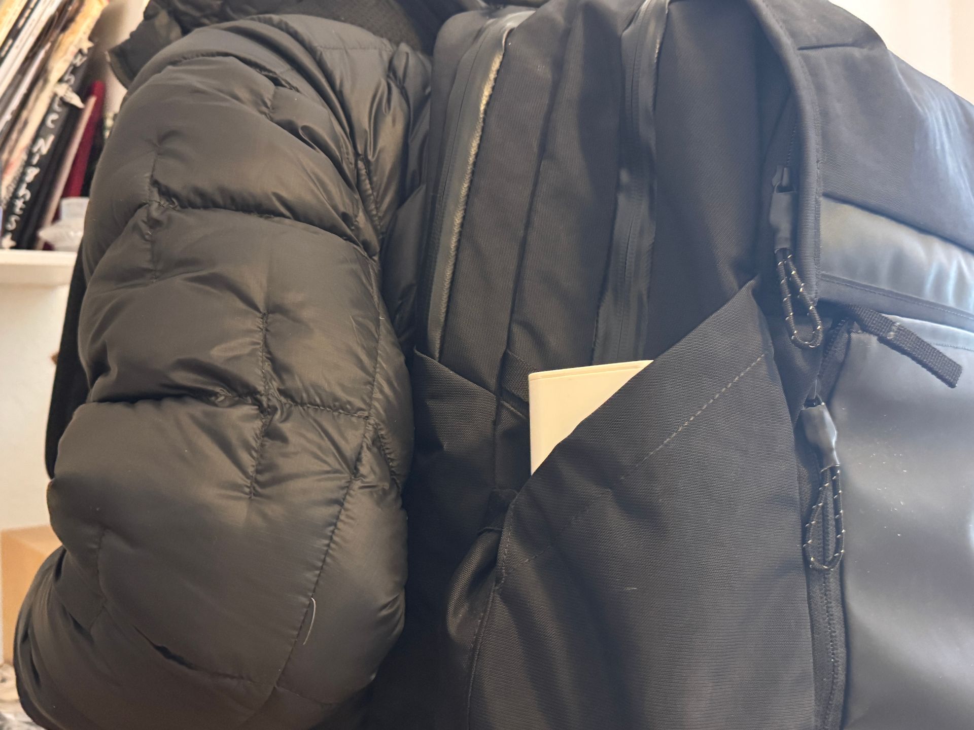 Black puffer jacket and backpack with a white card in side pocket.