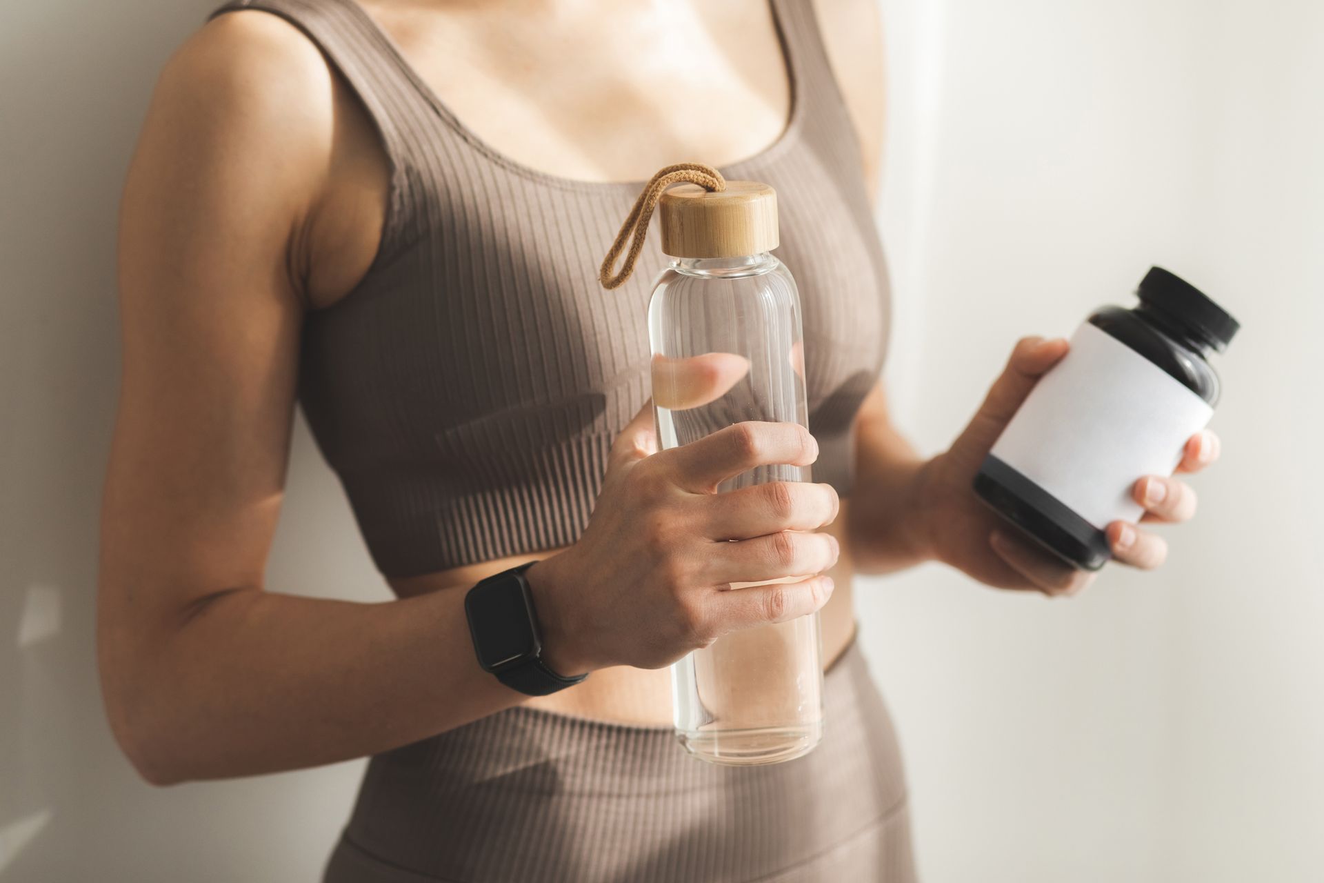 A man is taking a pill from a pill holder next to a glass of water.