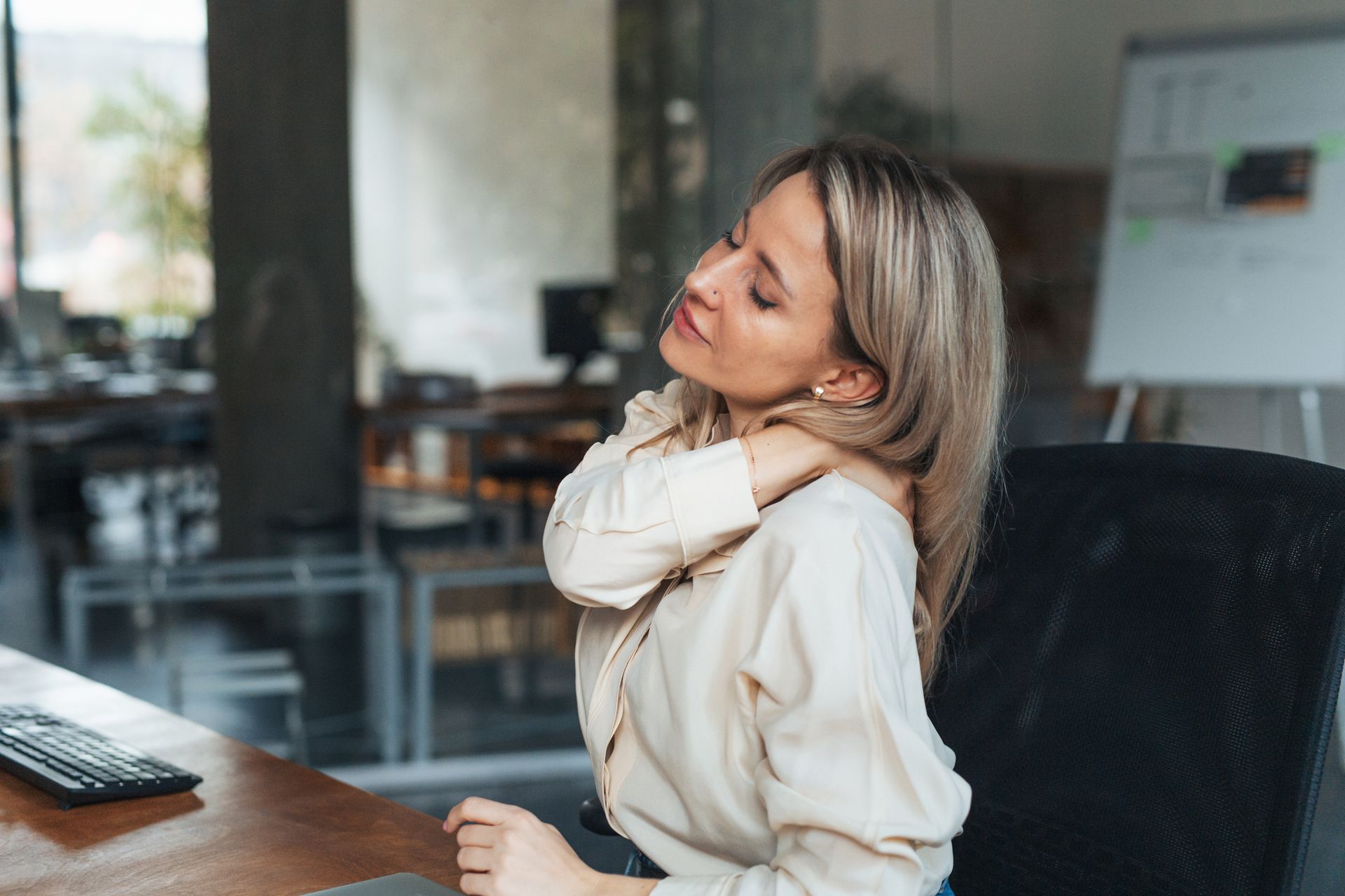 Woman with neck and shoulder pain from computer work, highlighting pain management needs.