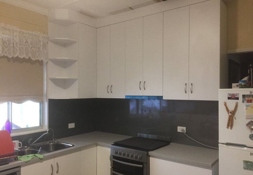 A kitchen with white cabinets , a stove , a sink , and a refrigerator.