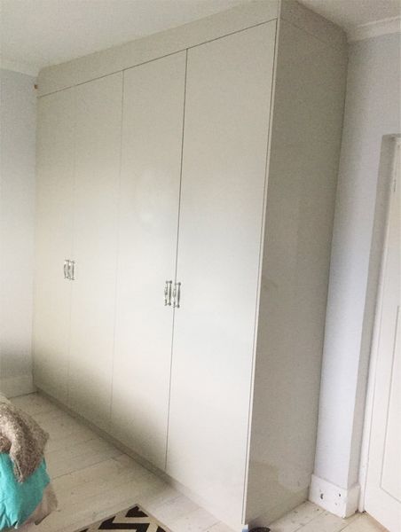 A person is standing in front of a large white cabinet in a room.