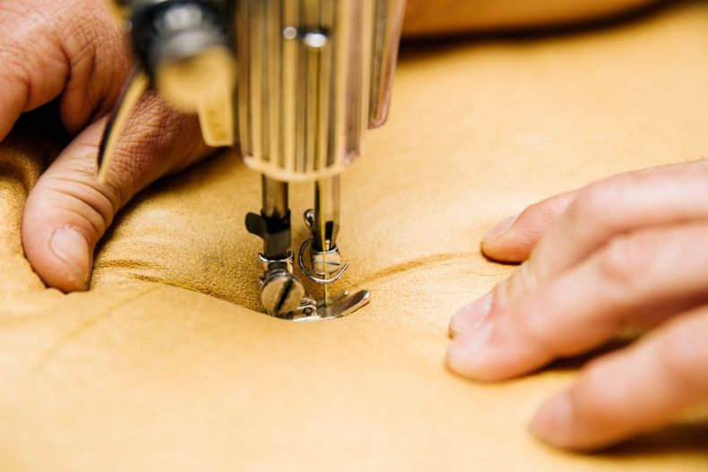 Hands sewing tan fabric with a sewing machine close-up