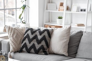 Cozy gray sofa with patterned throw pillows in a bright living room with white shelving
